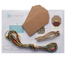 Contents of cross stitch gift tag kit including pattern, tags, hanging twine needle and threads.