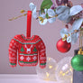 Red, white and green Christmas jumper bauble hanging on branch