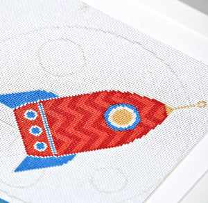 Close up of red and blue moon rocket cross stitched