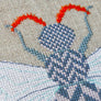 Close up of herringbone design cross stitches within the insect upper body and wings