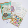Items included in the cross stitch kit including kit materials including packaging, threads, aida, pattern and needle