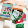 Cross stitch kit contents to create Christmas sprout including packaging, aida, felt, ribbon, thread and stuffing