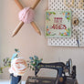 Cross stitch banner hanging on pegboard with wool and sewing machine