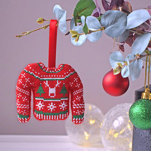 Red, white and green Christmas jumper bauble hanging on branch