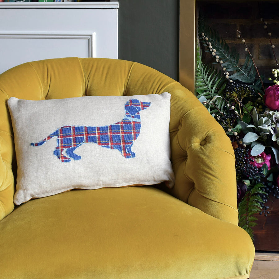 Cross stitched tartan dachshund cushion on a mustard velvet armchair