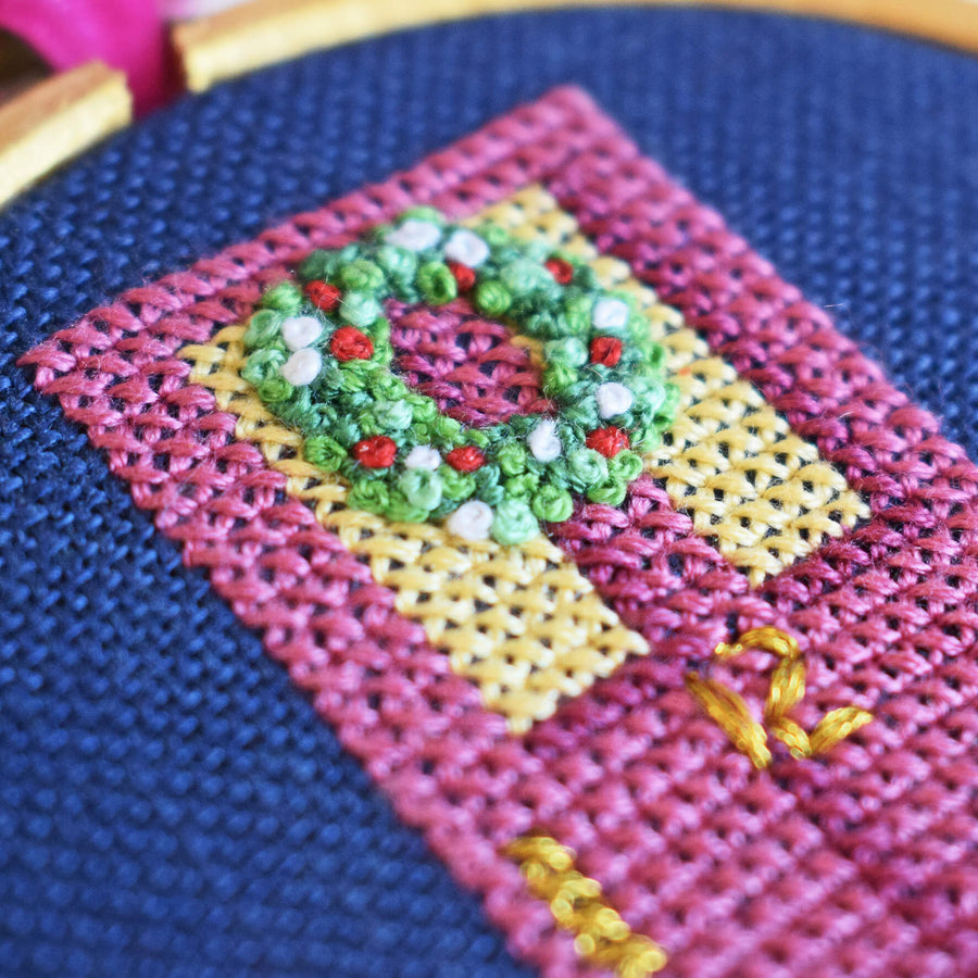 Close up of French knot Christmas wreath on cross stitched front door