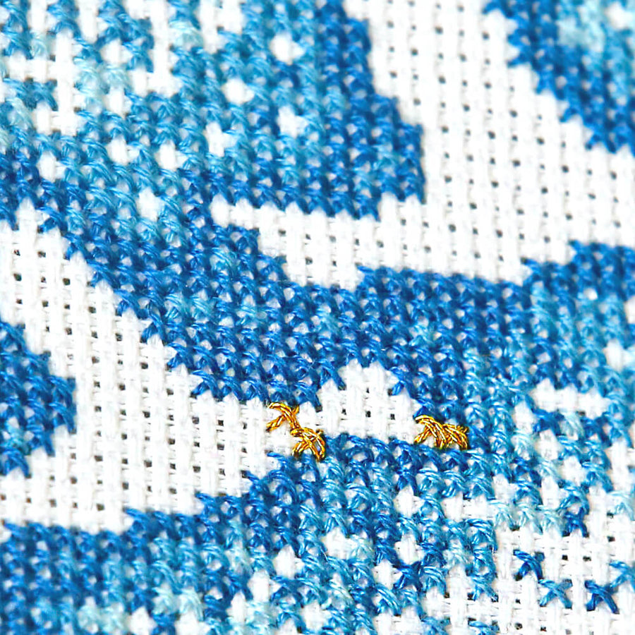 Close up of cross stitch duck outline including stitched metallic gold collars