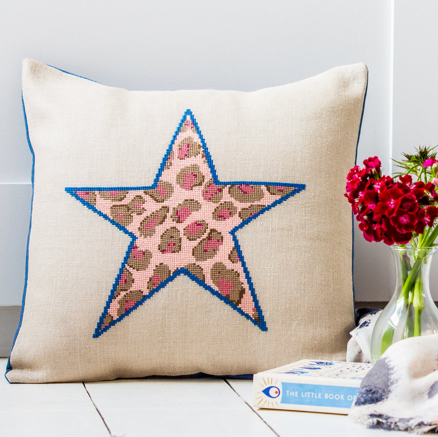 Cross stitch star design filled with pink leopard print made up into a cushion