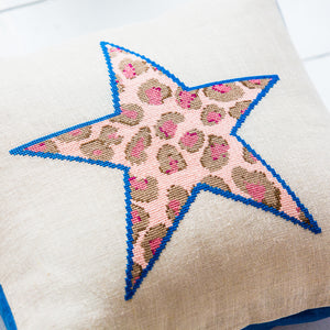 Close up of the cross stitched detail of a dark blue star outline filled with pink leopard print pattern