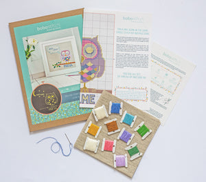 Items included in the cross stitch kit including kit materials including packaging, threads, aida, pattern and needle