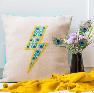 Cross stitch design of lightning bolt filled with peacock feathers made into a cushion.