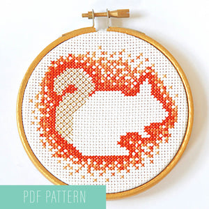 Cross stitch squirrel pattern - negative space with orange stitches around the outside
