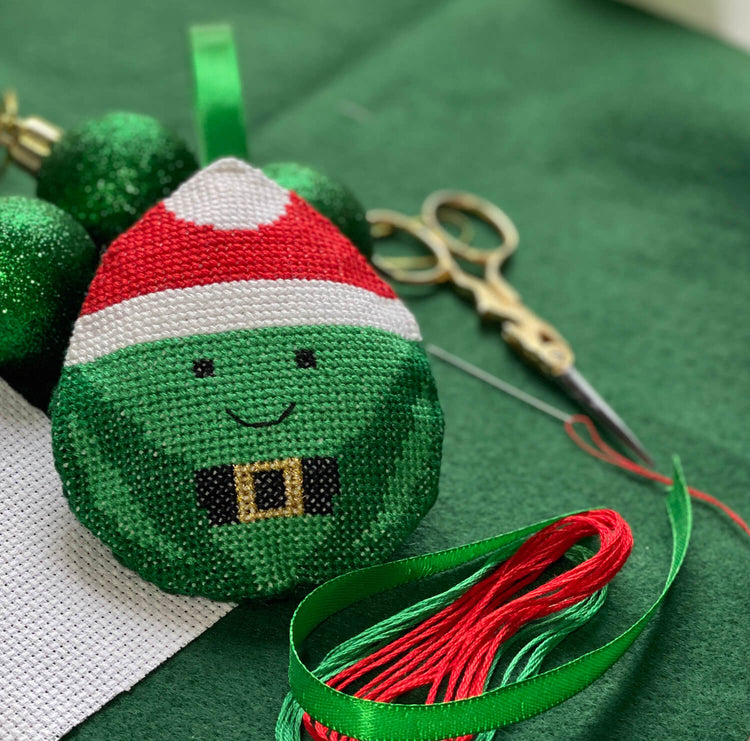 Cross stitch Christmas decoration on green felt with ribbons and scissors