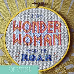Cross stitched pattern Wonder WomanHear Me Roar in 6 inch hoop sitting on gold patterned cushion